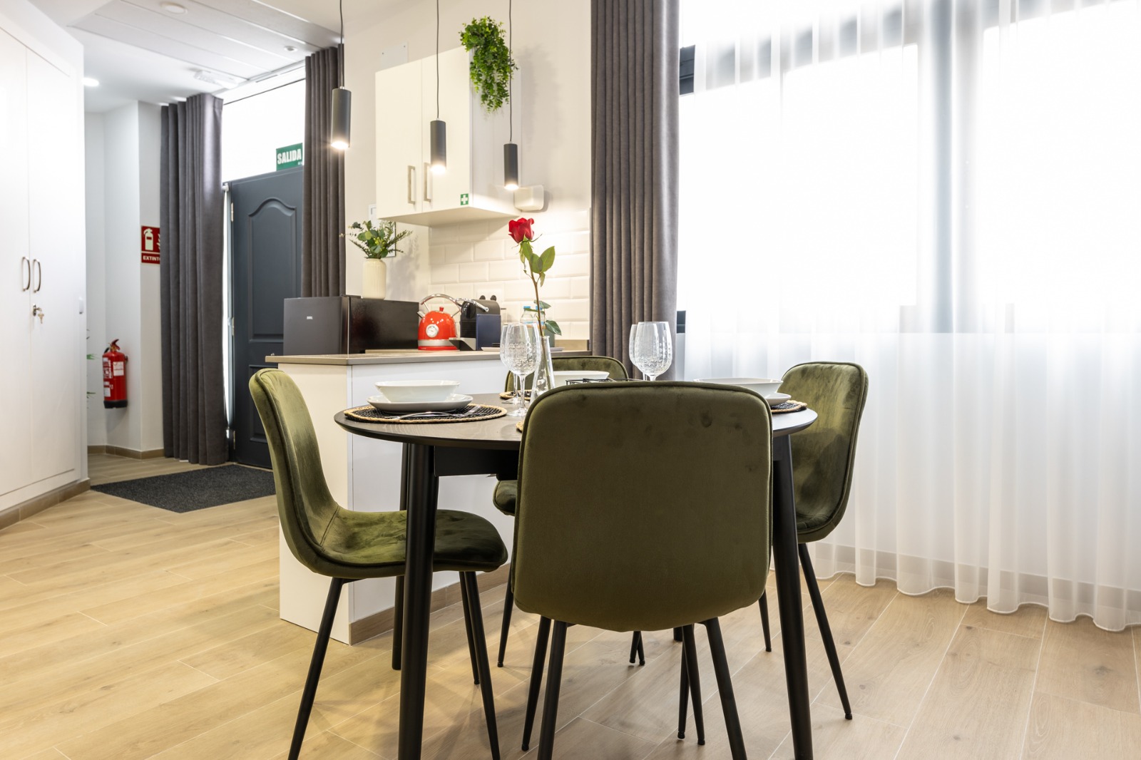 Cocina y comedor de apartamento con cortinas grises y visillo blanco