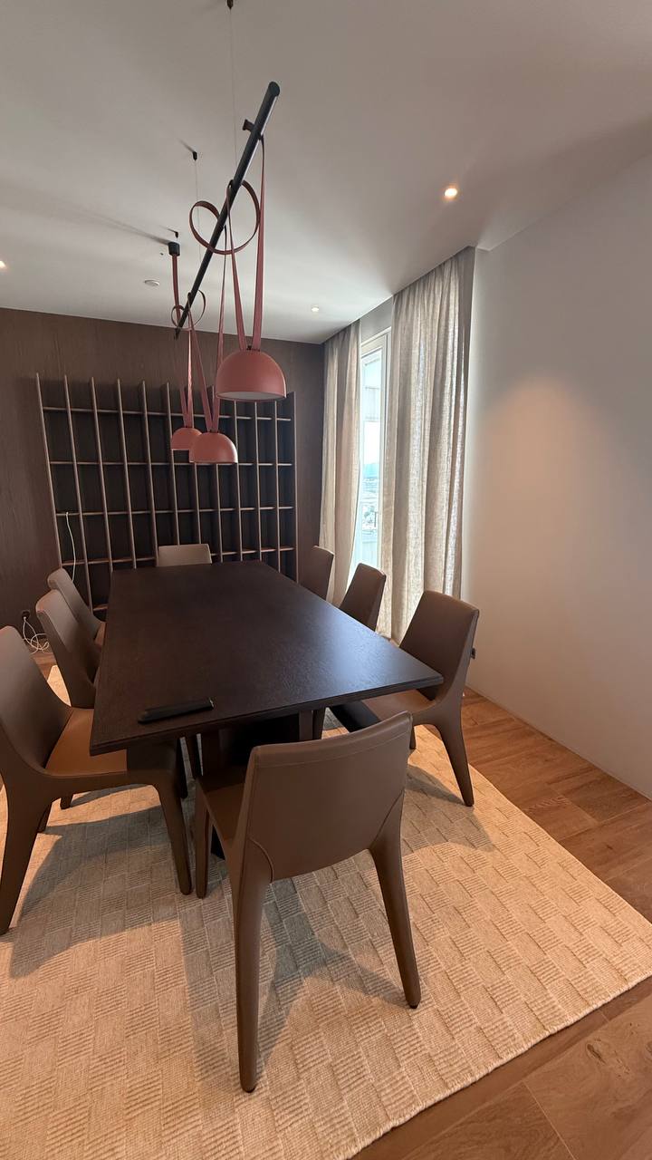Comedor con cortina de lino claro en el ventanal y mesa de madera oscura