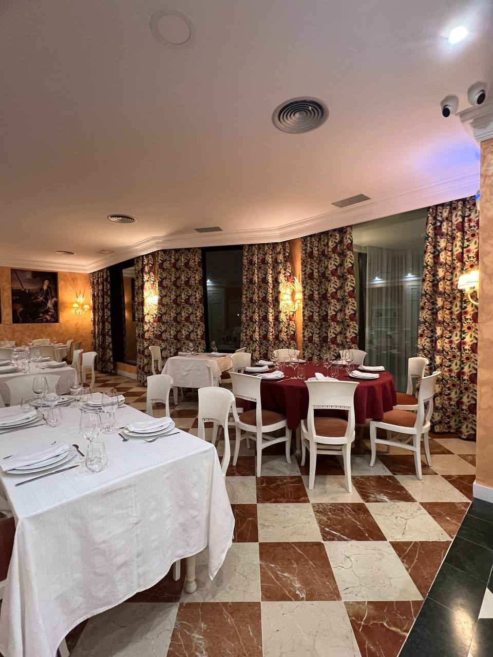 Comedor de restaurante con cortinas de tejido estampado y mantelería blanca