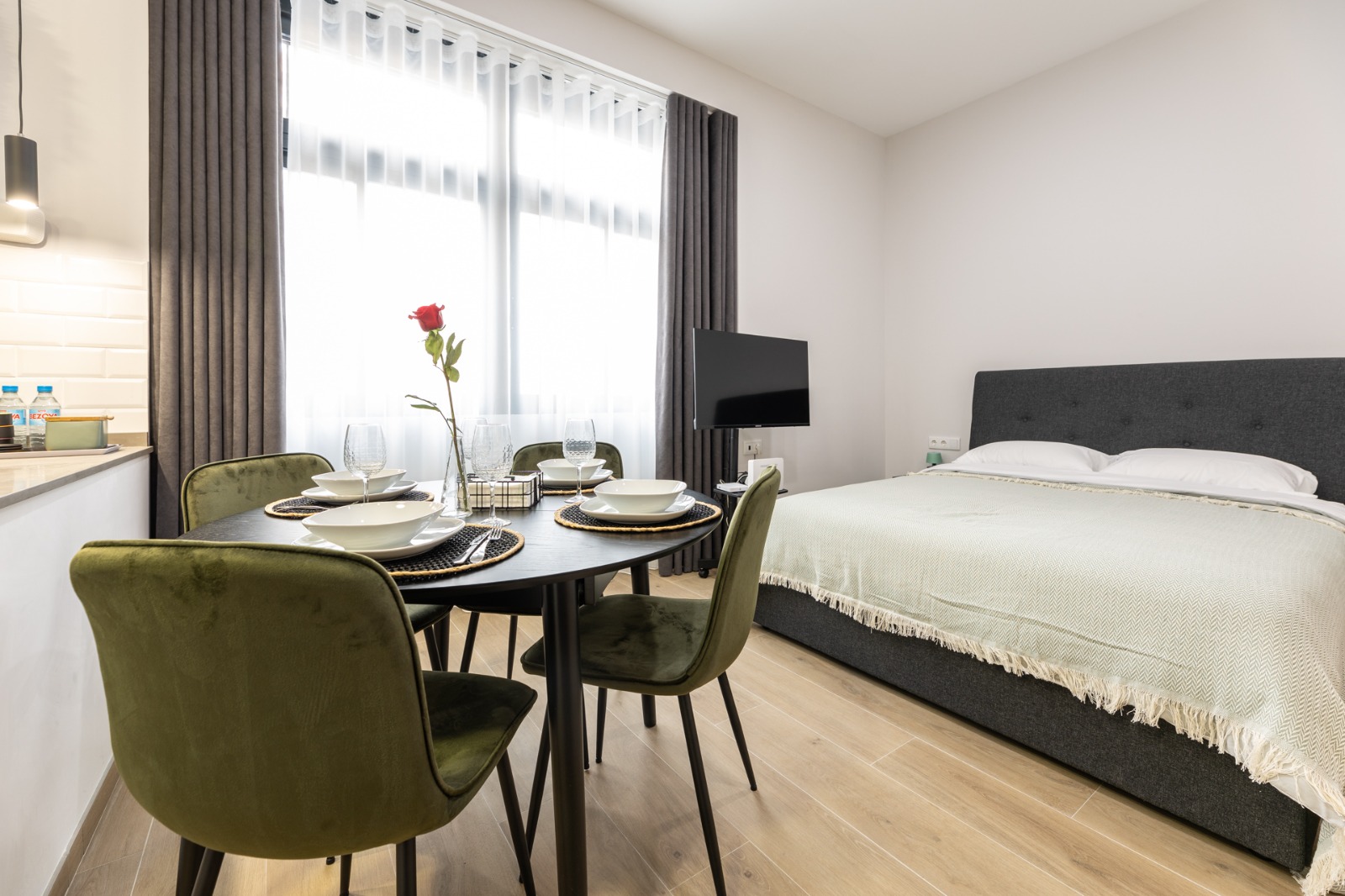 Estudio con zona de comedor y dormitorio, cortinas grises y visillo translúcido