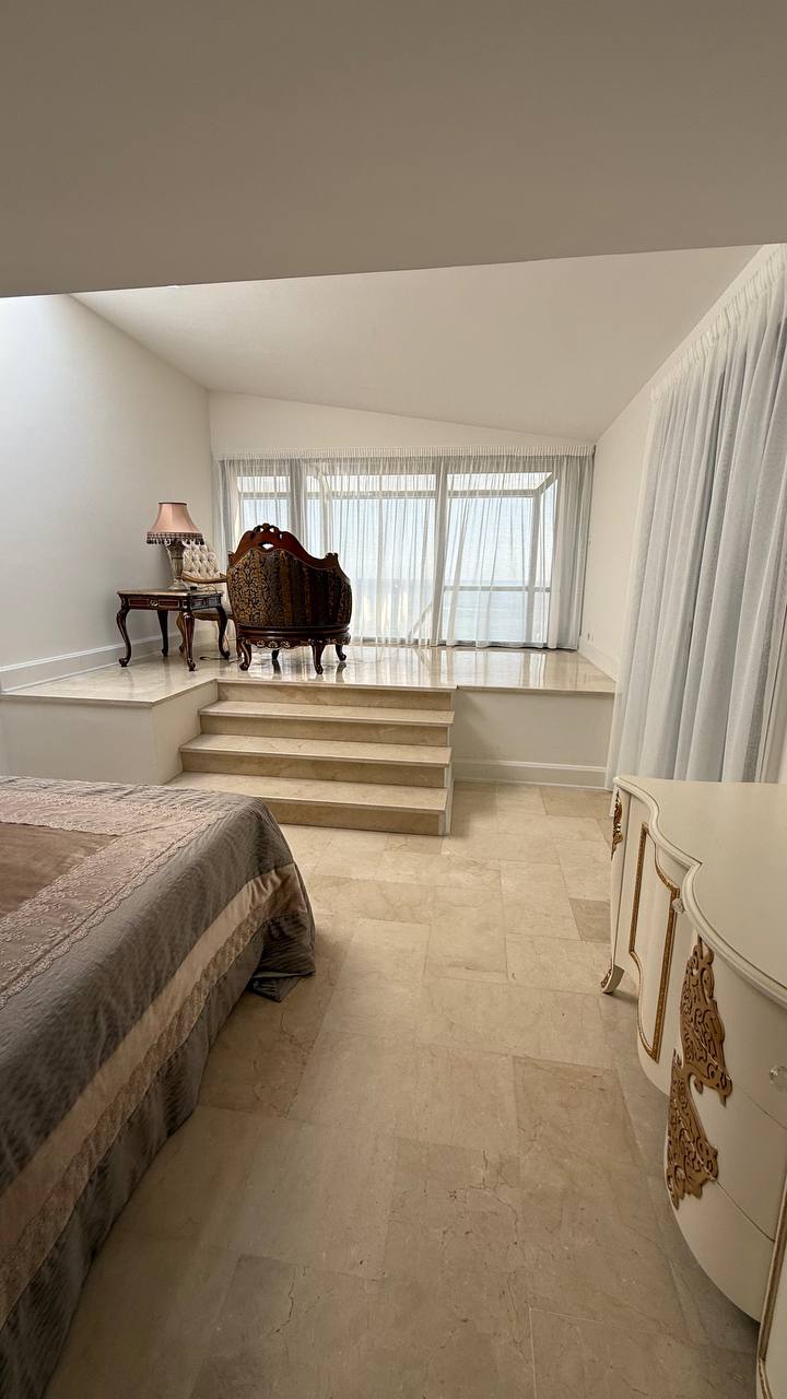Dormitorio amplio con visillos blancos en el ventanal elevado
