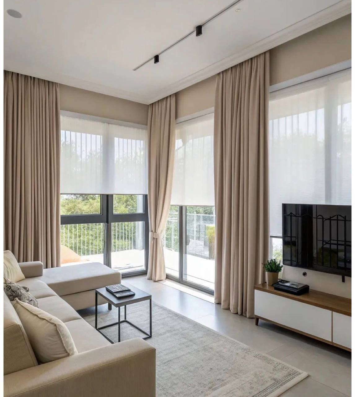 Salón con cortinas beige de suelo a techo combinadas con estores enrollables translúcidos