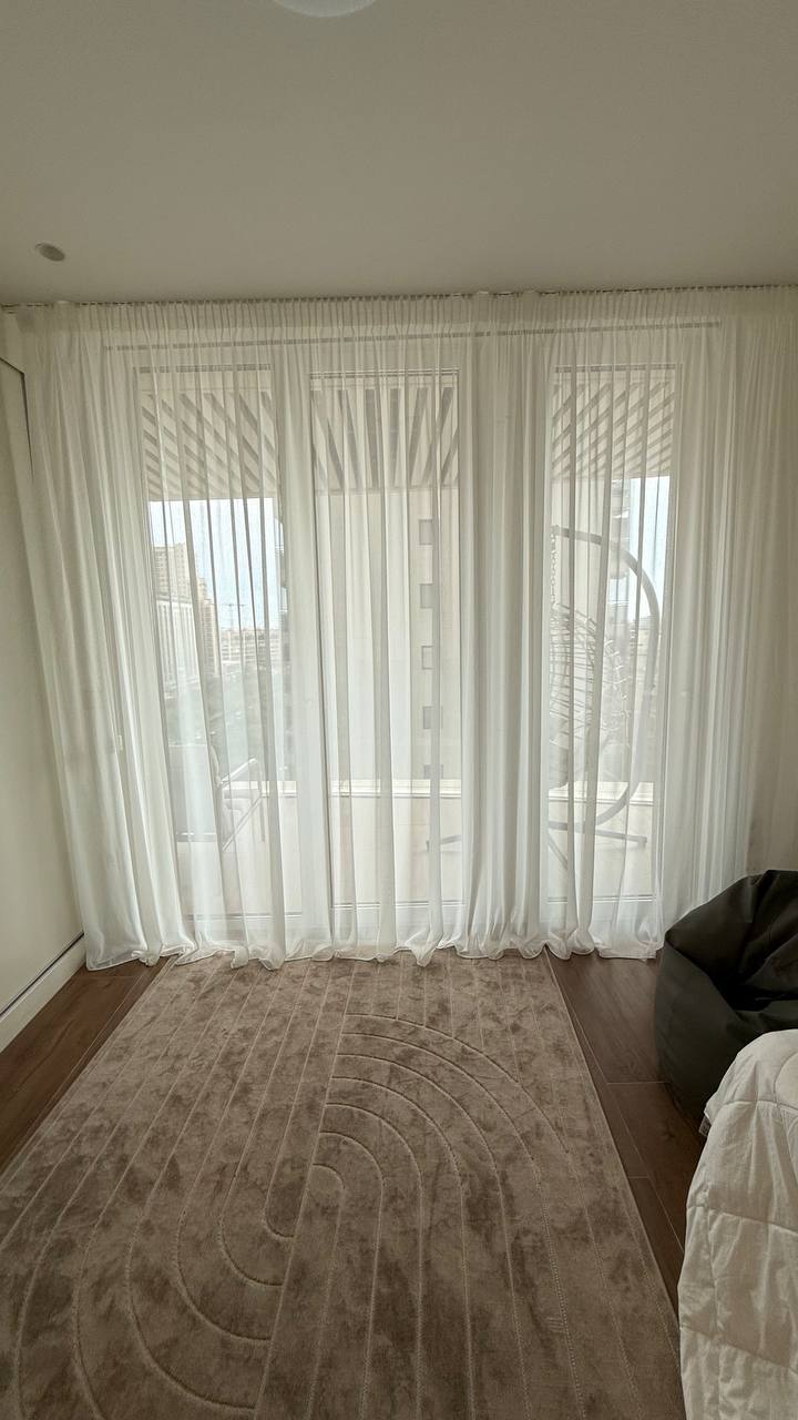 Visillos blancos de suelo a techo en un dormitorio con alfombra beige