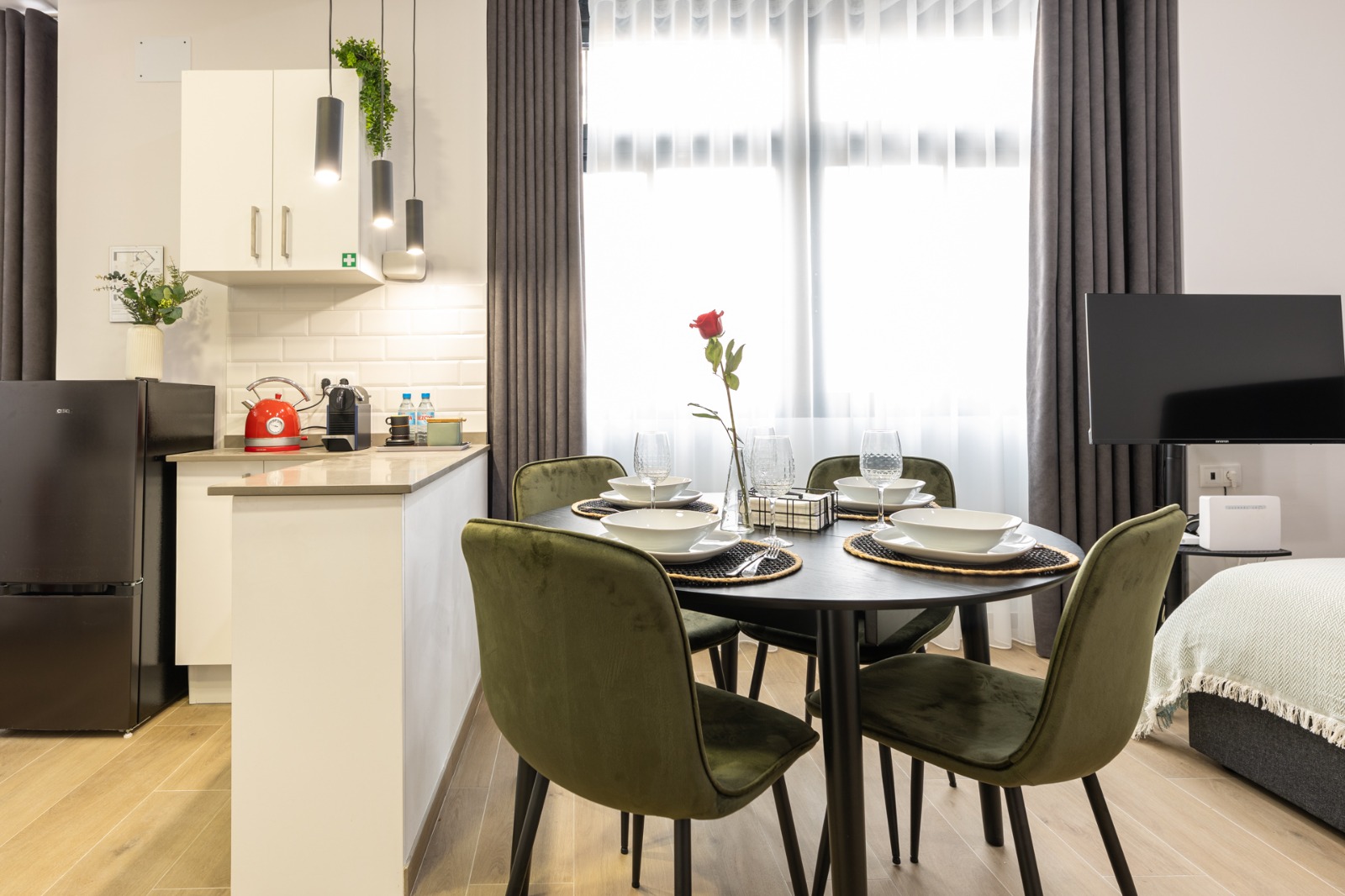Comedor de estudio con cortinas grises y visillo translúcido junto a la cocina