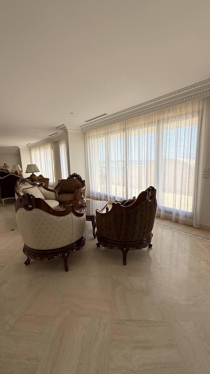 Salón con visillos crudos a lo largo de un ventanal continuo