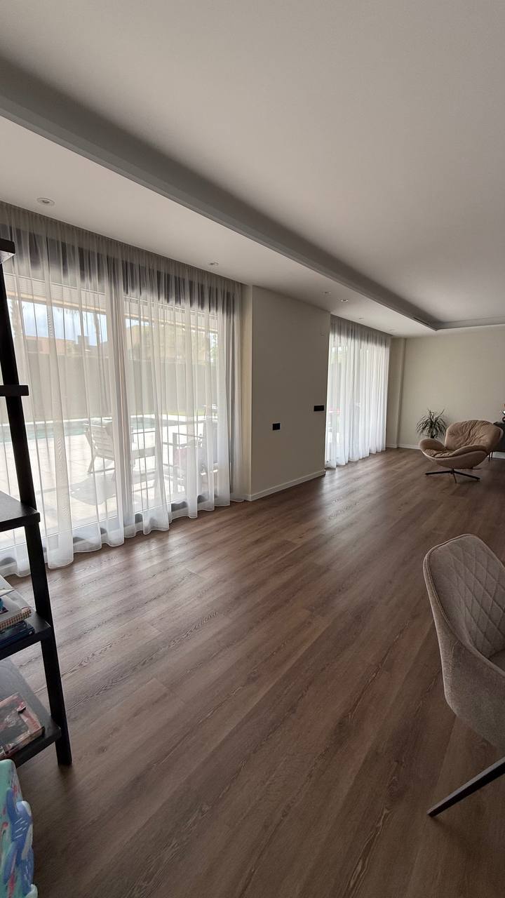 Salón diáfano con visillos blancos en los ventanales que dan a la piscina